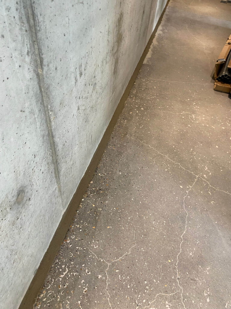 Betonvæg med nystøbt fuge langs gulvet